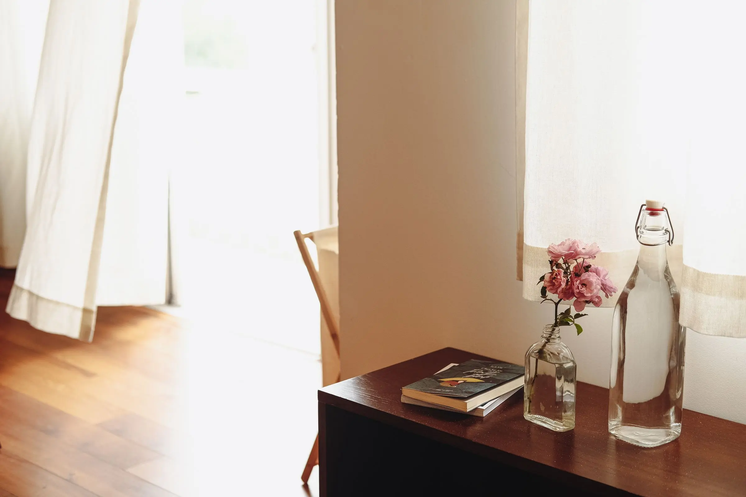 Soft light through curtains onto a wooden table with books